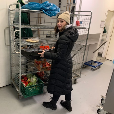 Eine Frau nimmt eine Kiste mit schwarzen Trauben aus einem Regal.