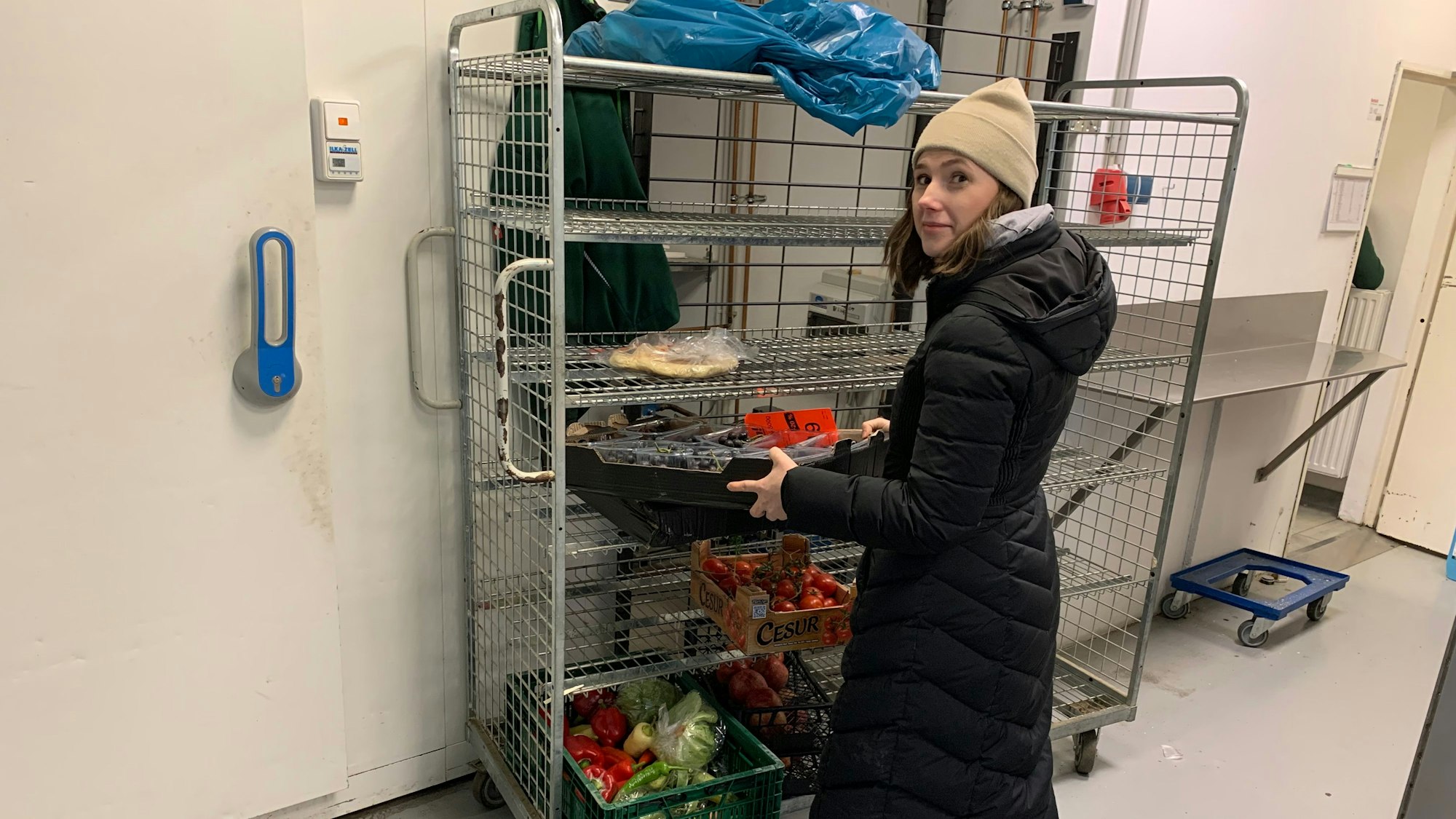 Eine Frau nimmt eine Kiste mit schwarzen Trauben aus einem Regal.