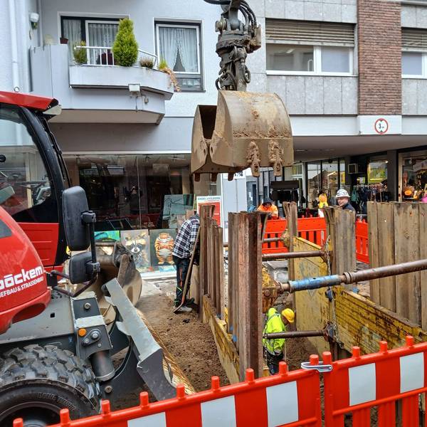 Ein roter Bagger neben einer Baugrube