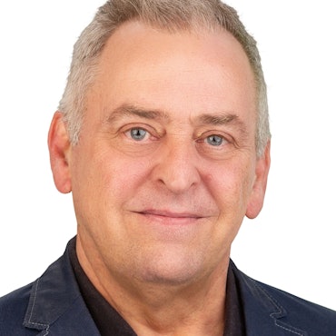 Ein Mann blickt lächelnd zur Kamera.