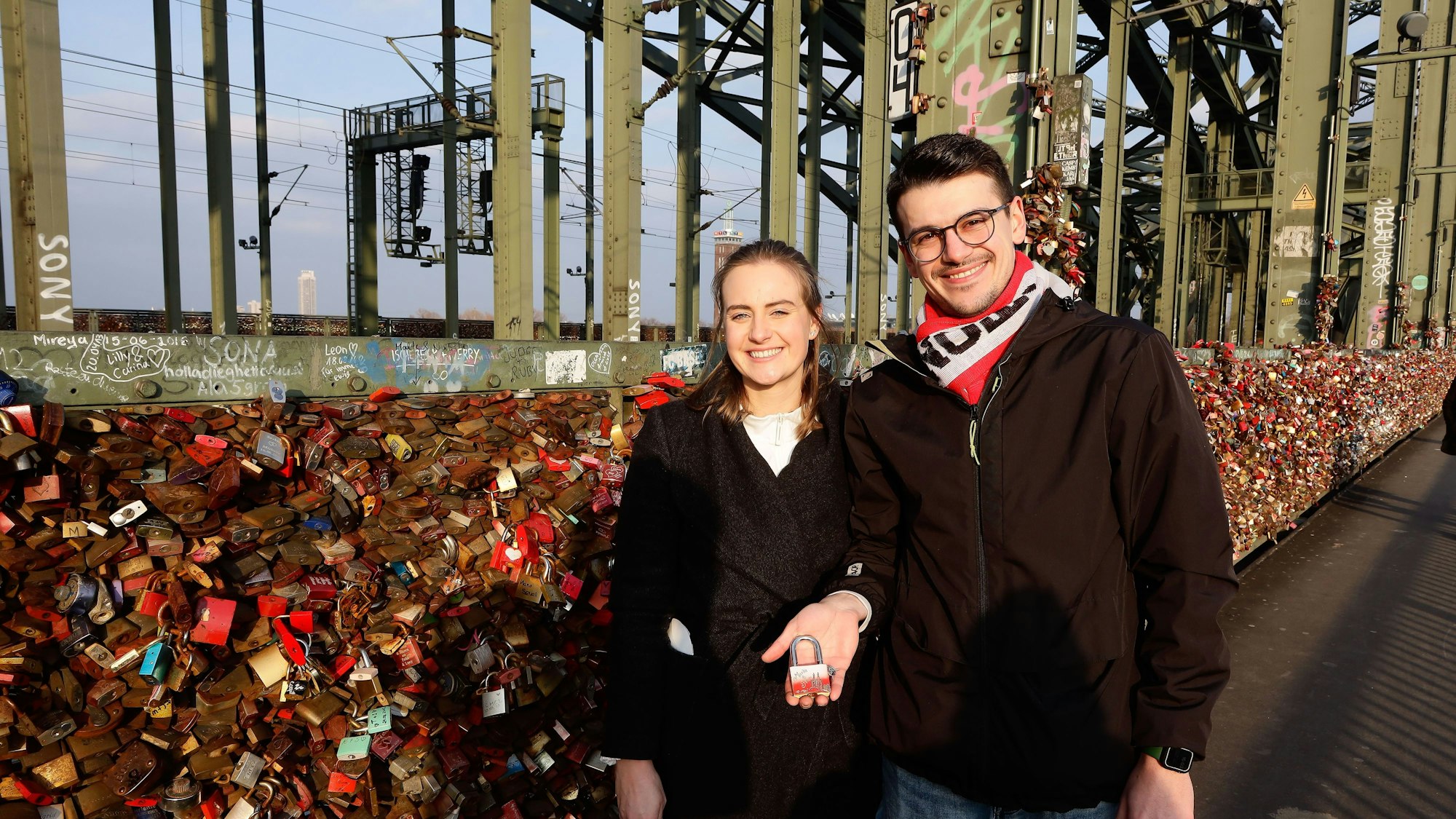 Marla Carus (26) und Sven Turi (26) bringen ihr Liebesschloss an der Kölner Hohenzollernbrücke an.