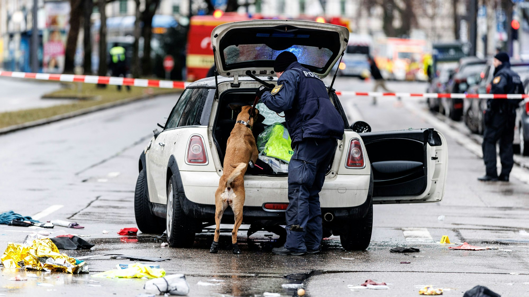 dpatopbilder - 13.02.2025, Bayern, München: Die Polizei untersucht mit einem Spürhund ein Auto unweit des Stiglmaierplatz. In der Münchner Innenstadt ist ein Fahrzeug in eine Menschengruppe gefahren. Foto: Matthias Balk/dpa +++ dpa-Bildfunk +++