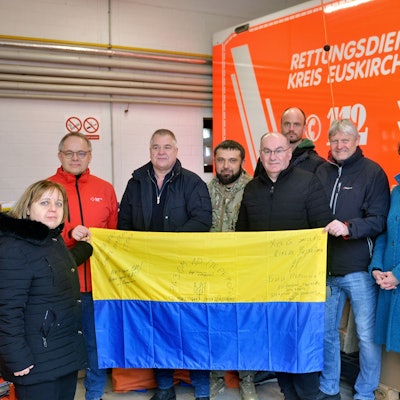 Oleksandr Popov und andere haben sich zu einem Foto aufgestellt. Sie halten eine Landesflagge der Ukraine ins Bild.