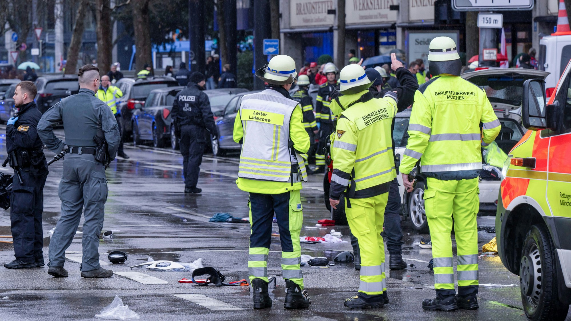 Feuerwehrleute und Polizisten stehen am Einsatzort in der Münchner Innenstadt, wo ein Fahrzeug in eine Menschengruppe gefahren ist.