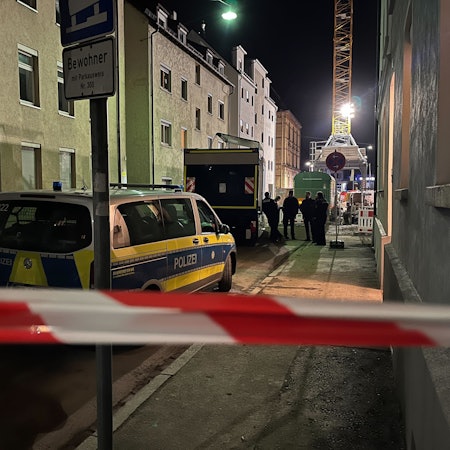 Einsatzkräfte und Einsatzwagen der Polizei hinter einer Absperrung. (Symbolfoto)