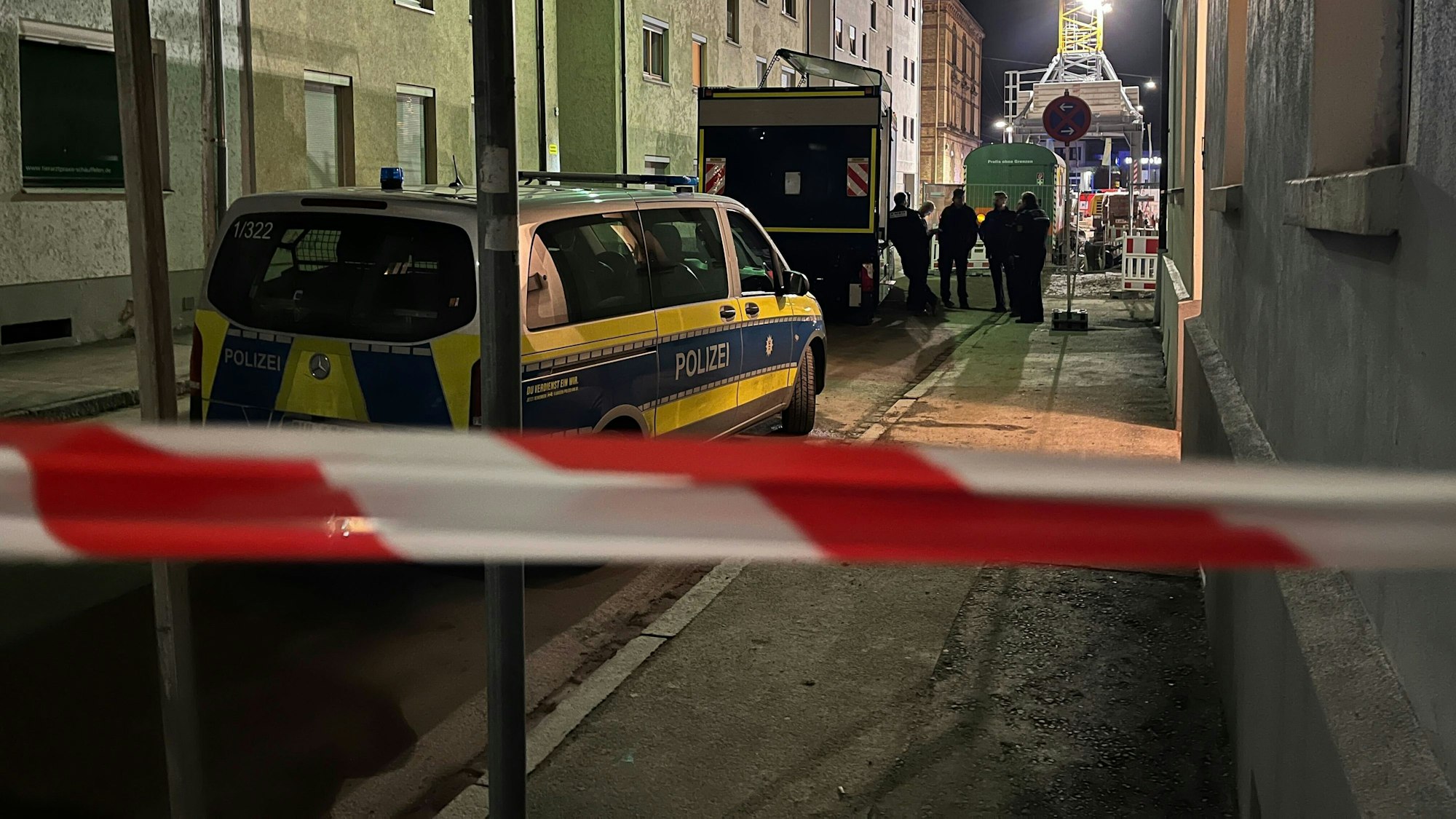Einsatzkräfte und Einsatzwagen der Polizei hinter einer Absperrung. (Symbolfoto)