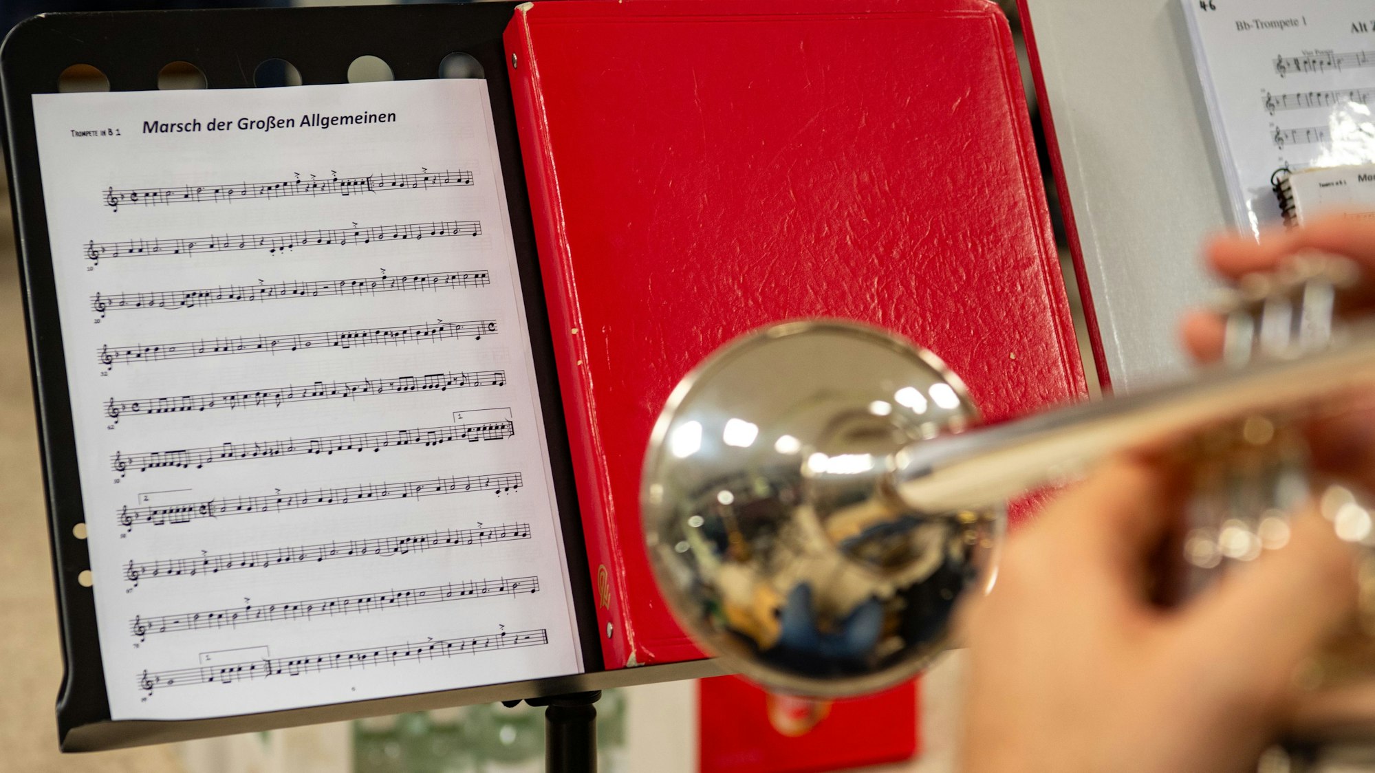 Auf einem Notenständer steht ein Notenblatt mit der Aufschrift „Marsch der Großen Allgemeinen“.