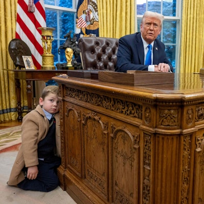 Elon Musks Sohn X Æ A-Xii lehnt am Schreibtisch von US-Präsident Donald Trump.