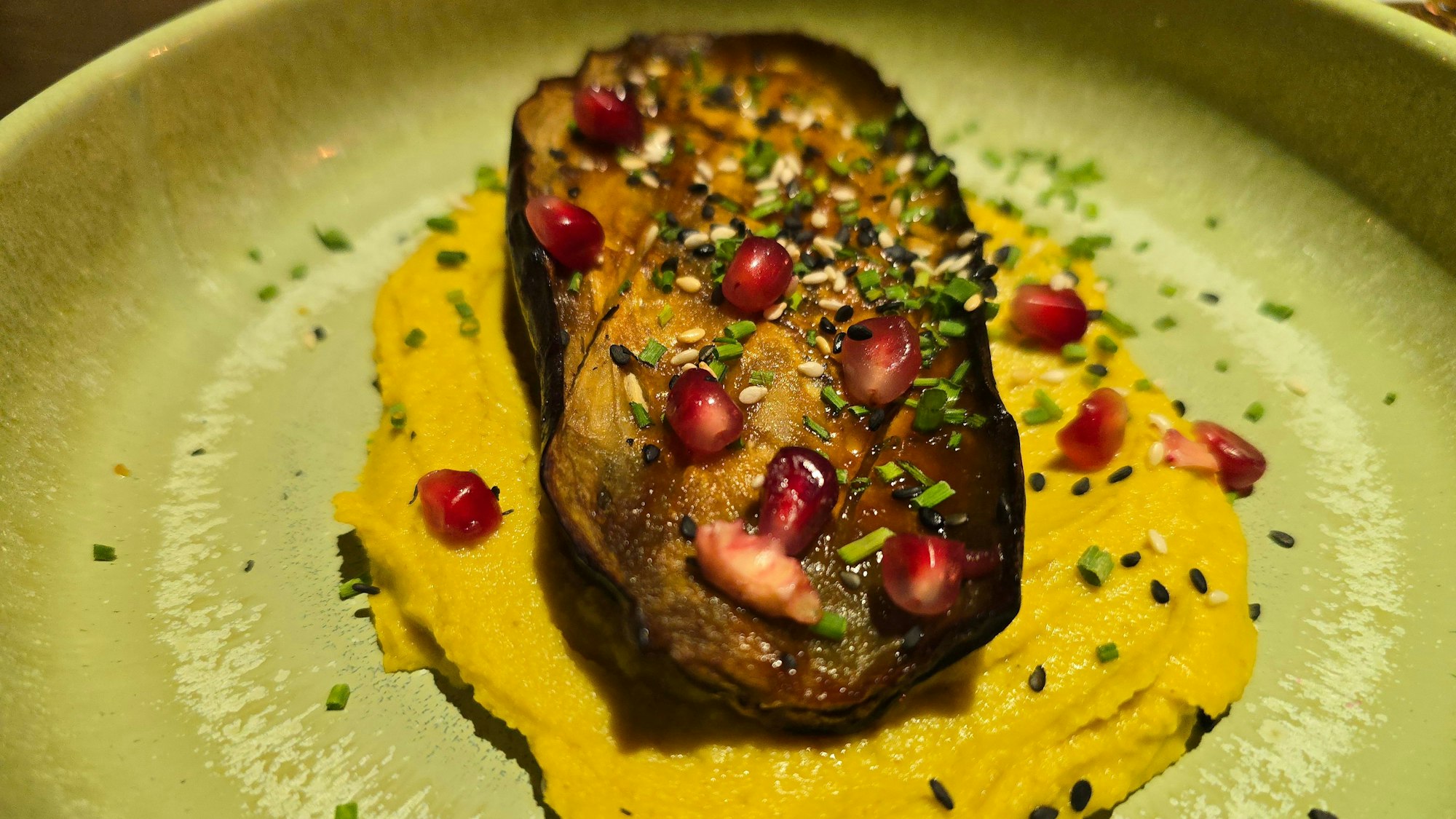 Ein Tellergericht mit Aubergine auf einem Hummus platziert.