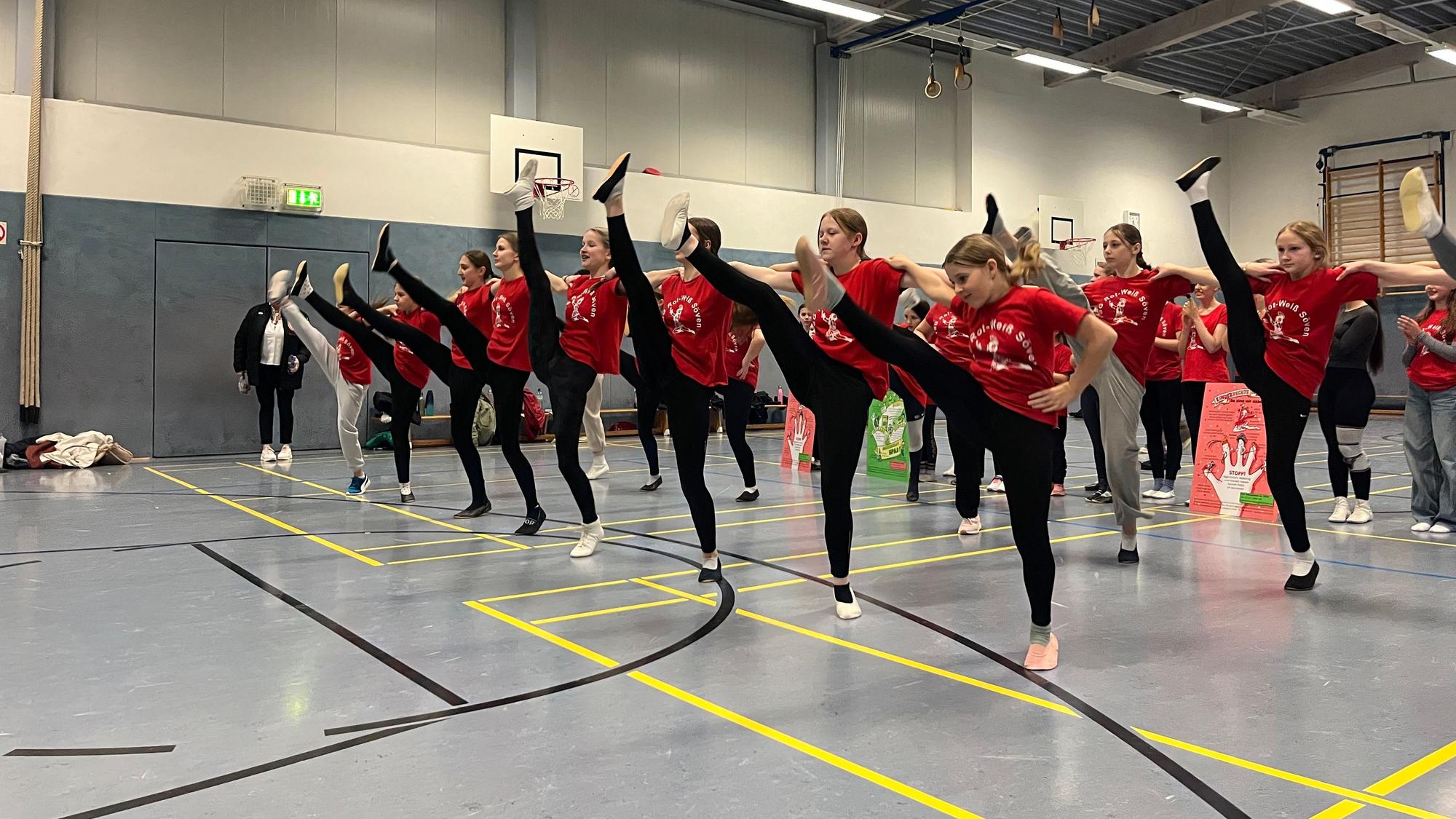 Junge Tänzerinnen werfen beim Training ihre Beine in die Höhe.