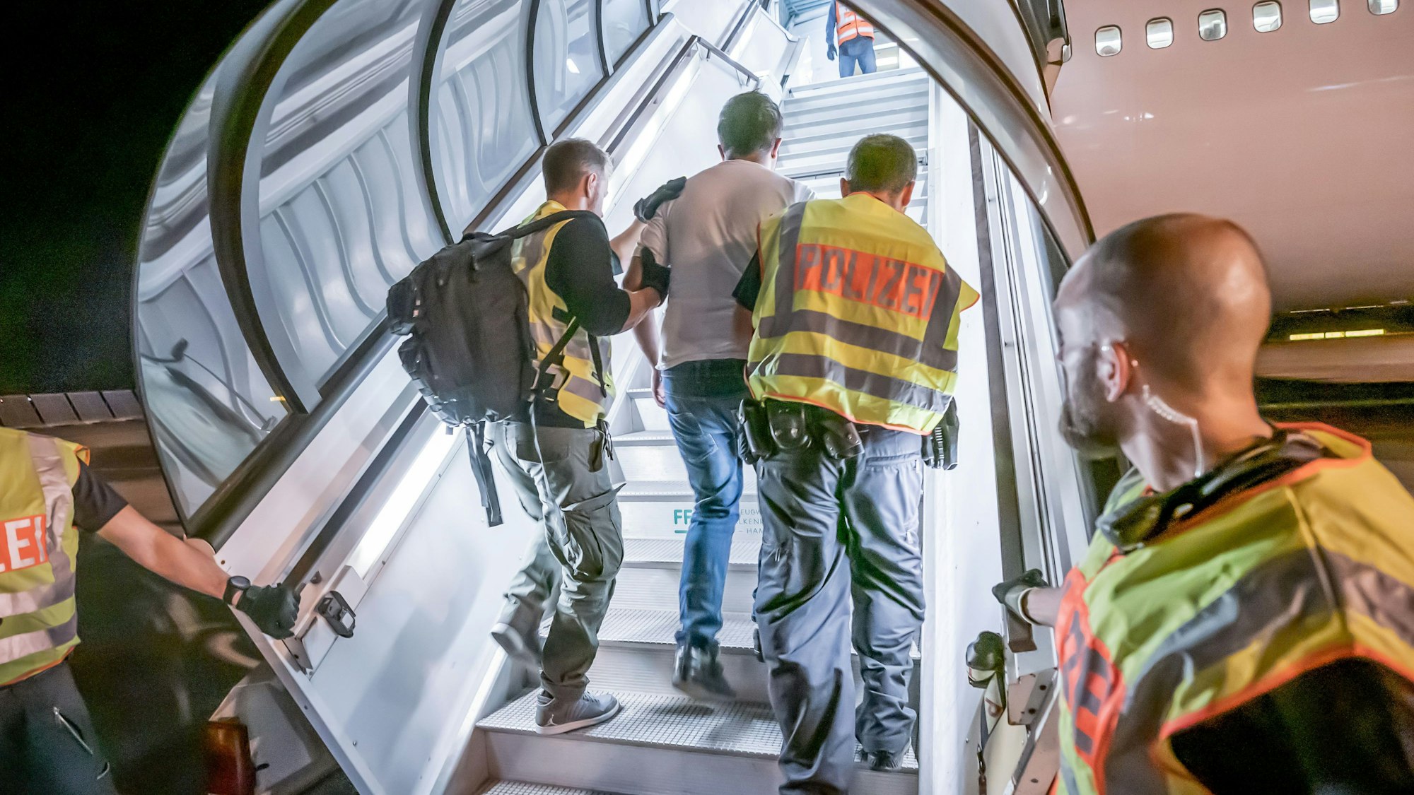 Polizeibeamte begleiten einen Afghanen in ein Charterflugzeug. In einzelnen Fällen werden Menschen aus Afghanistan abgeschoben