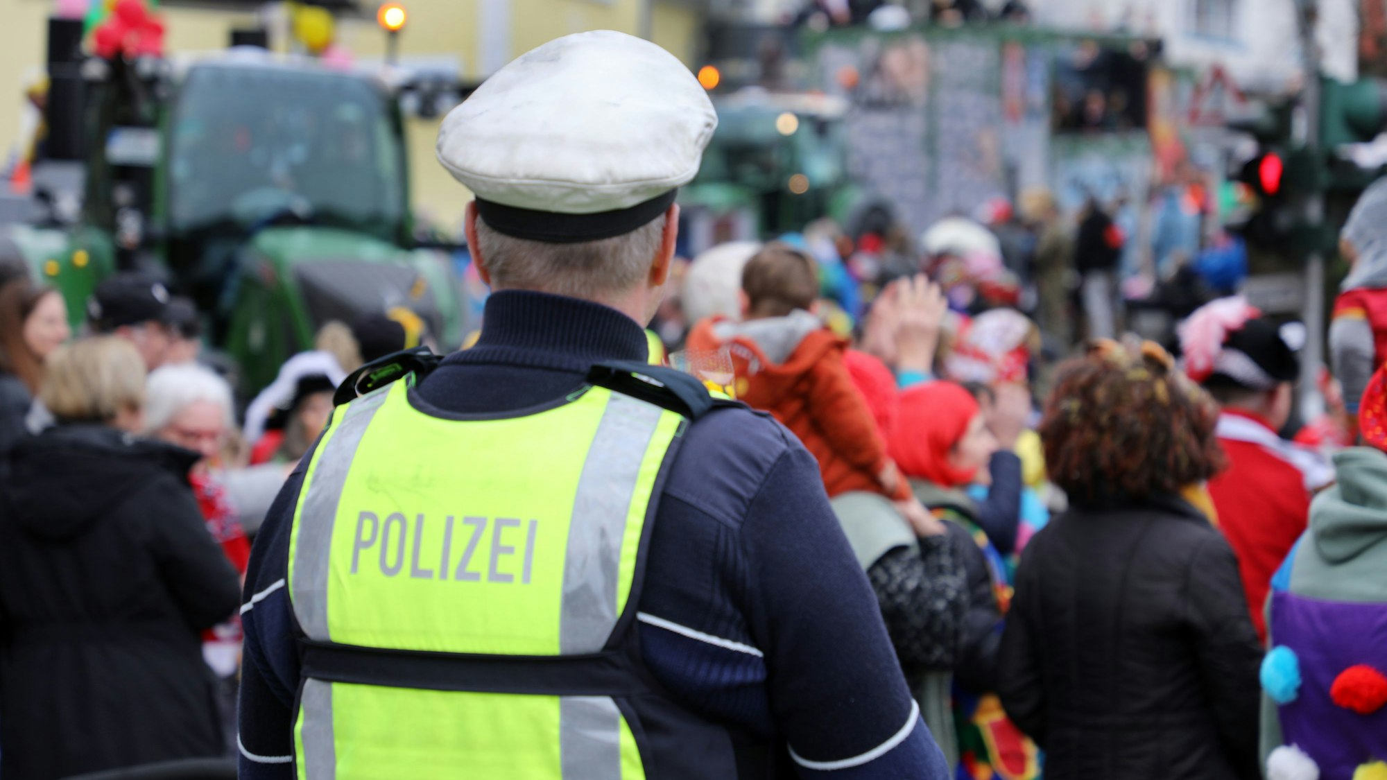 Ein Polizist beobachtet die feiernde Menge am Rande eines Karnevalzuges.