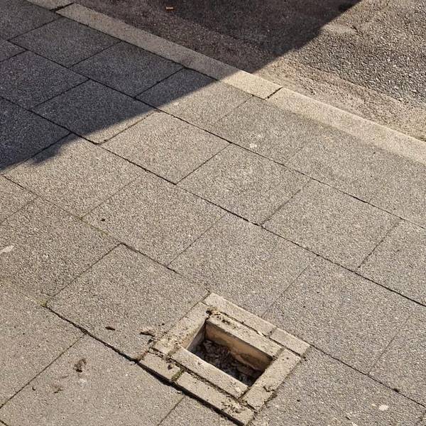 Zu sehen ist eine Lücke in einem Gehwegpflaster, in dem Steine fehlen.