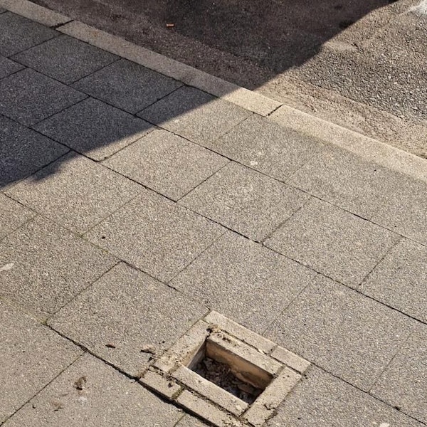 Zu sehen ist eine Lücke in einem Gehwegpflaster, in dem Steine fehlen.