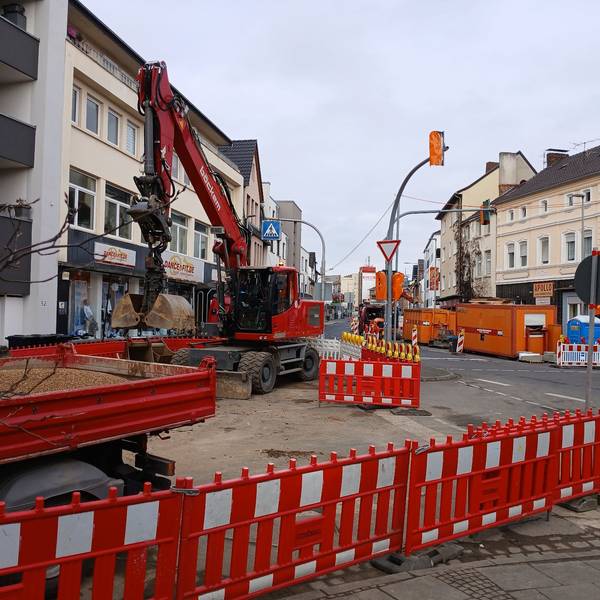 Eine Straßenbaustelle mit Absperrungen und Bagger.