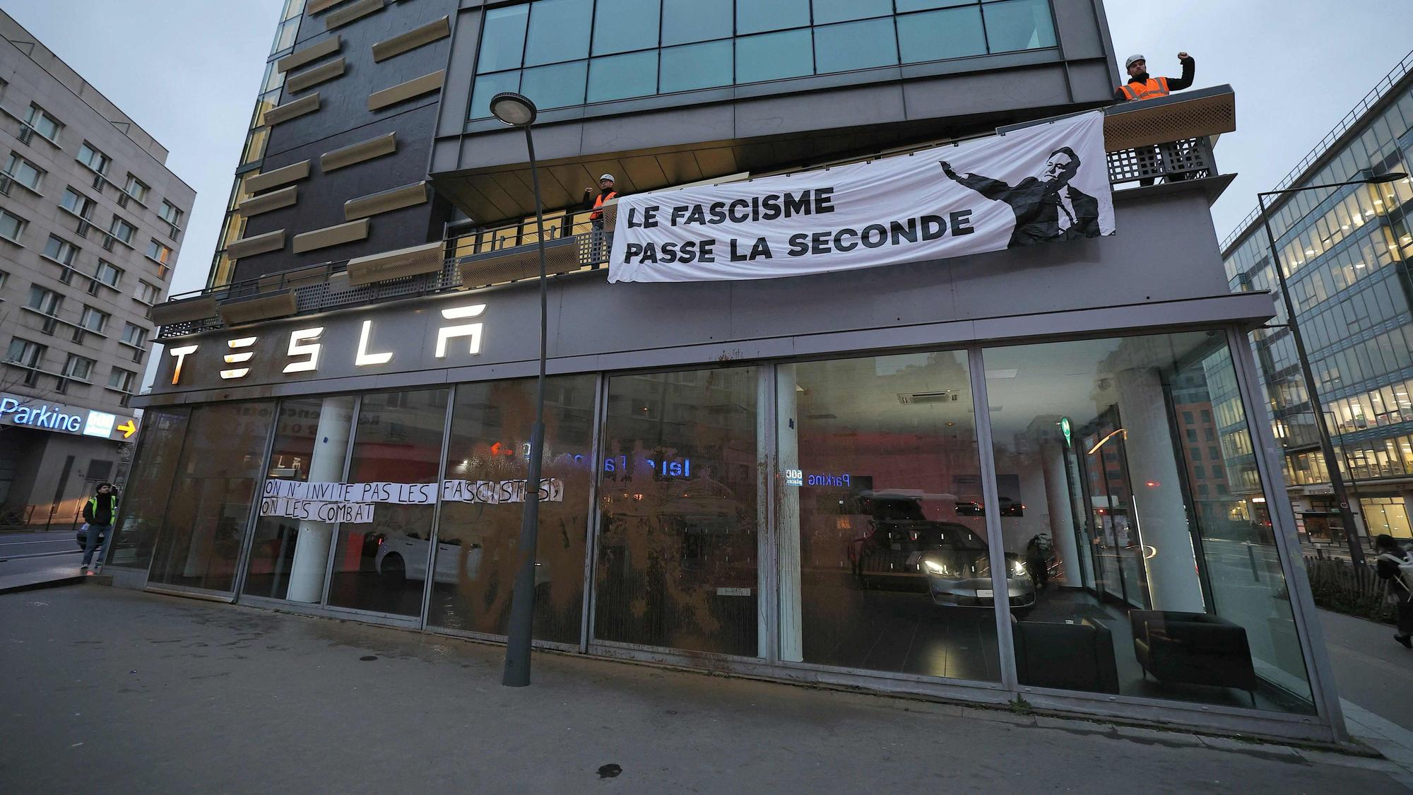Aktivisten haben Plakate mit der Aufschrift ‚Wir laden keine Faschisten ein, wir kämpfen gegen sie‘ und ‚Faschismus schaltet in den zweiten Gang‘ an der Fassade des Hauptsitzes des US-Autobauers Tesla in Frankreich angebracht. Sie protestieren damit gegen Elon Musk. (Archivbild)