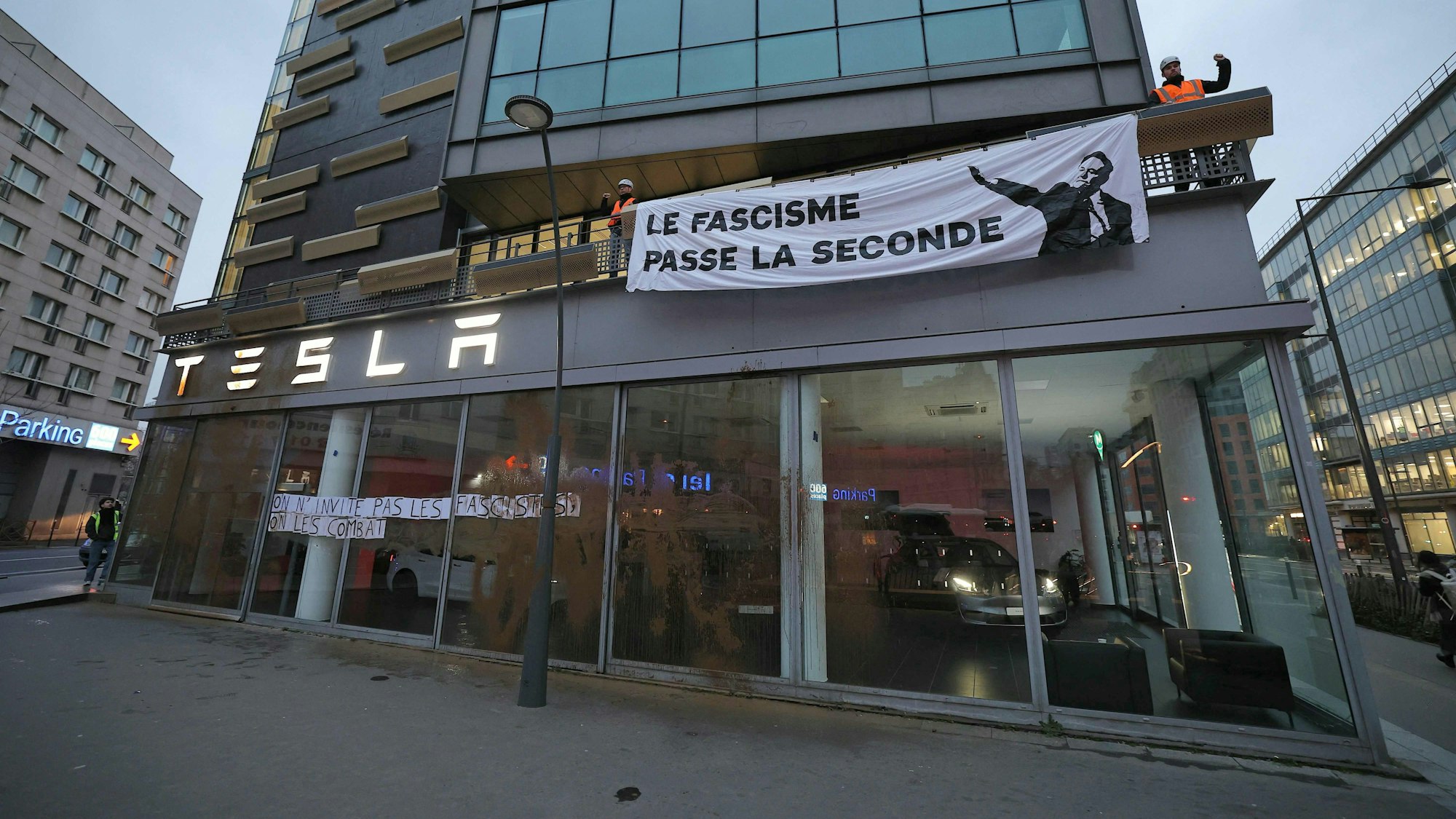Aktivisten haben Plakate mit der Aufschrift ‚Wir laden keine Faschisten ein, wir kämpfen gegen sie‘ und ‚Faschismus schaltet in den zweiten Gang‘ an der Fassade des Hauptsitzes des US-Autobauers Tesla in Frankreich angebracht. Sie protestieren damit gegen Elon Musk. (Archivbild)