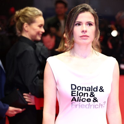 Luisa Neubauer, Aktivistin, steht am Eröffnungsabend der Berlinale auf dem Roten Teppich und trägt ein Kleid mit der Aufschrift „Donald & Elon & Alice & Friedrich?“.