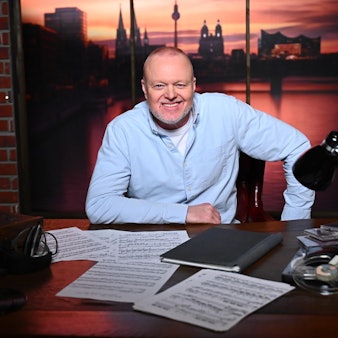 Stefan Raab sitzt an einem Schreibtisch.