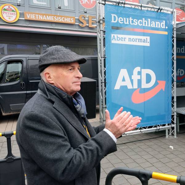 AfD-MdB Rüdiger Lucassen applaudiert neben einem Banner mit dem AfD-Emblem.