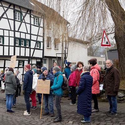 Auf dem Platz vor einem Fachwerkhaus stehen Menschen zu einer Mahnwache für die Demokratie  zusammen. Manche tragen Schilder.