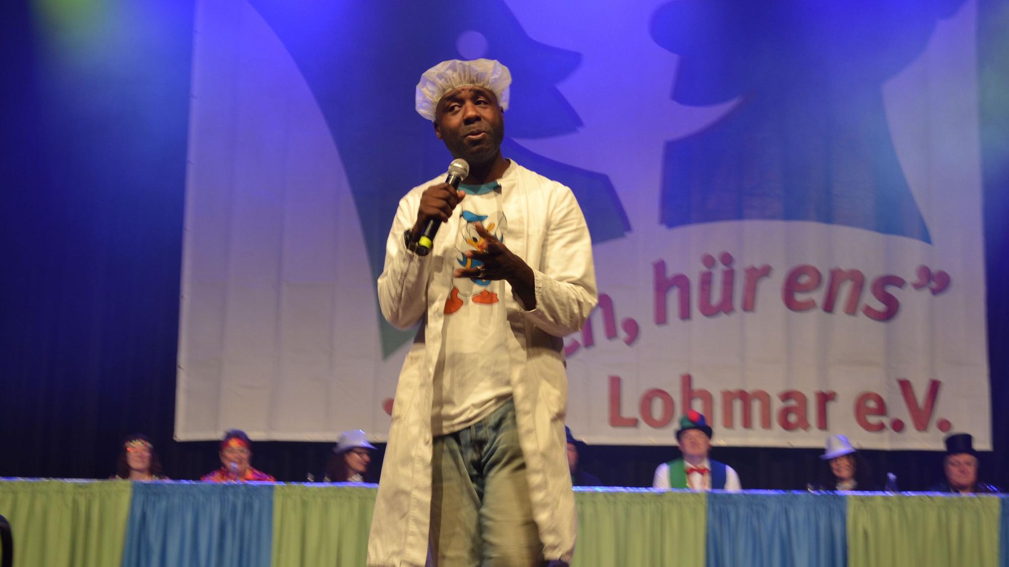 Ein Mann steht bei einer Karnevalssitzung auf der Bühne
