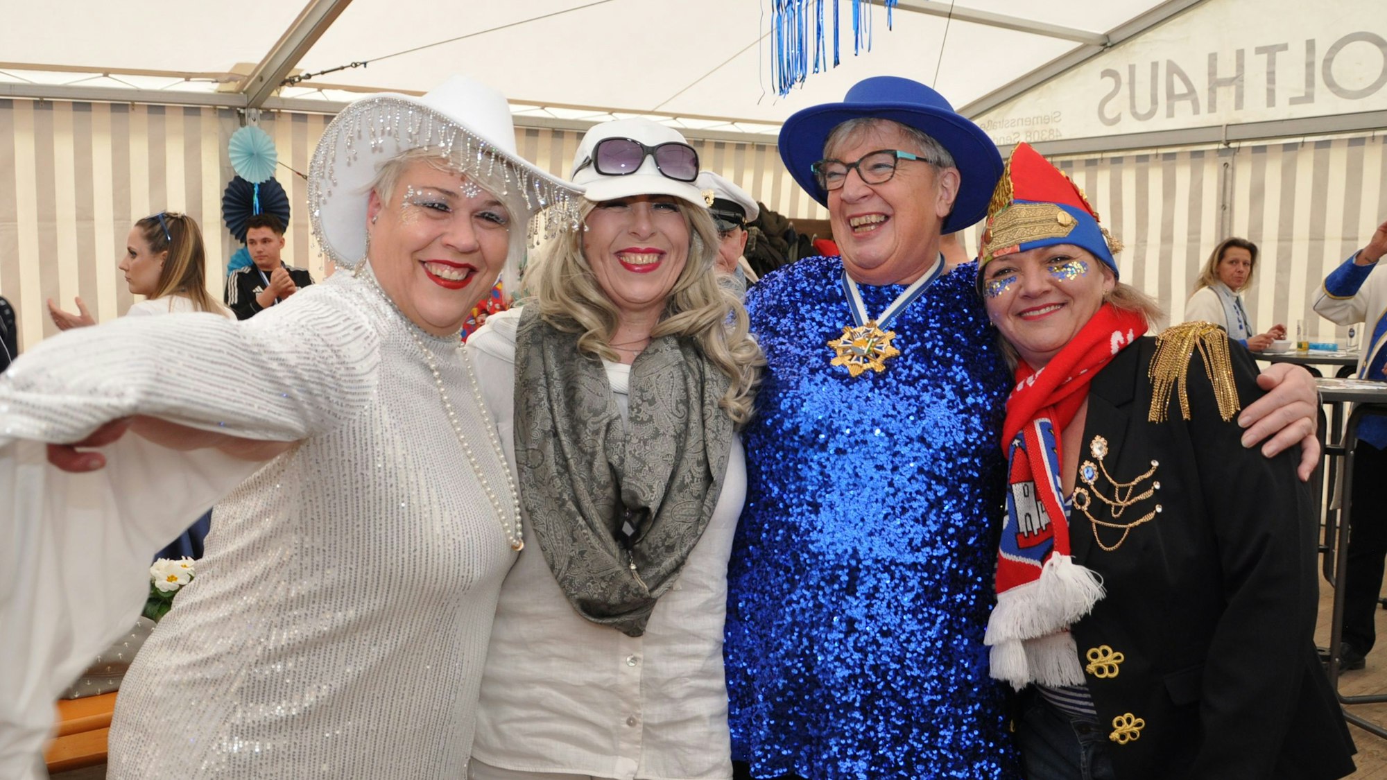 Kostümierte Menschen halten sich in den Armen und lachen.