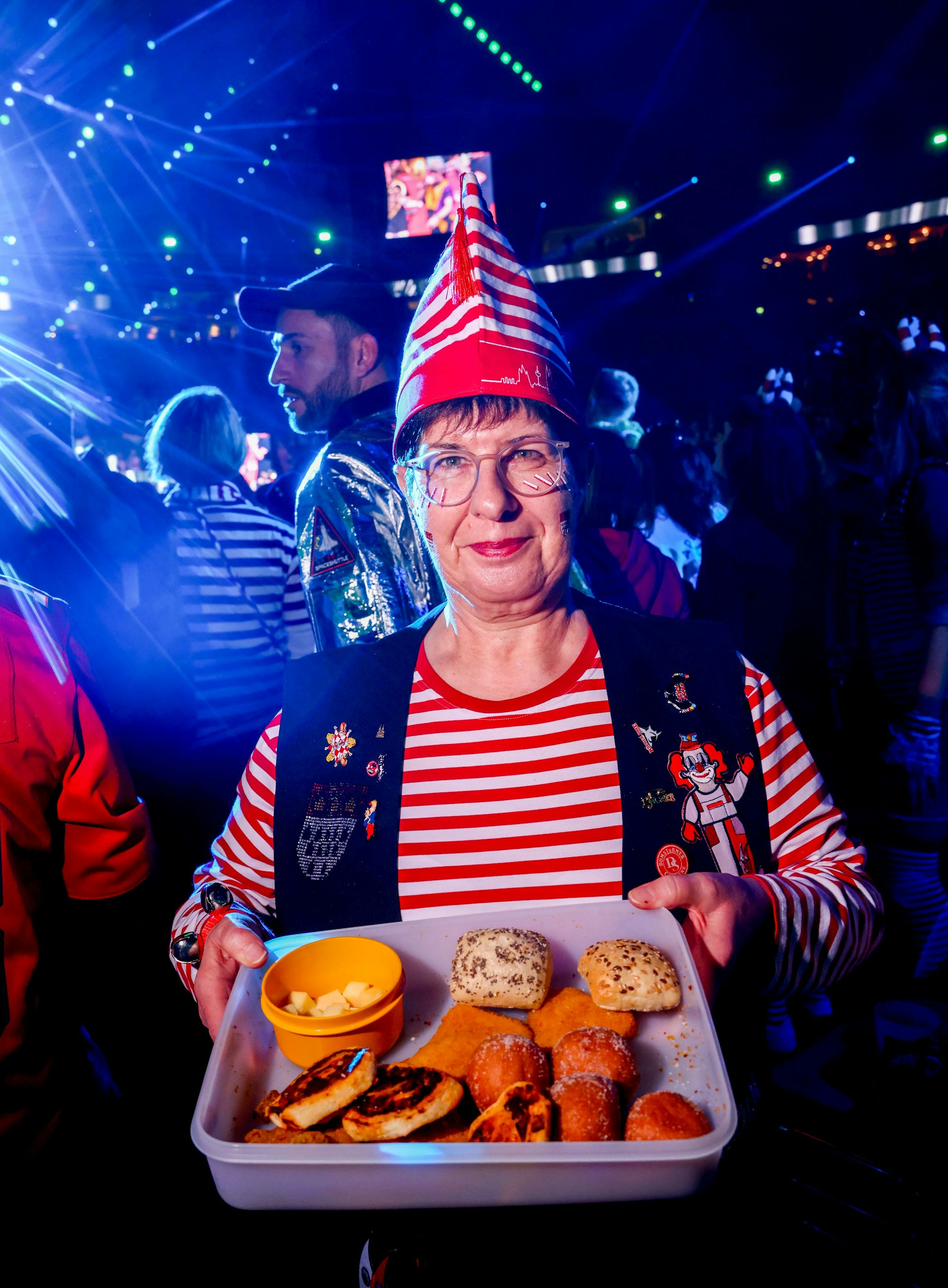 Frau hält Tupperdose mit Quarkbällchen, Pizzaschnecken, Mini-Schnitzel, Käsewürfel und Brötchen.