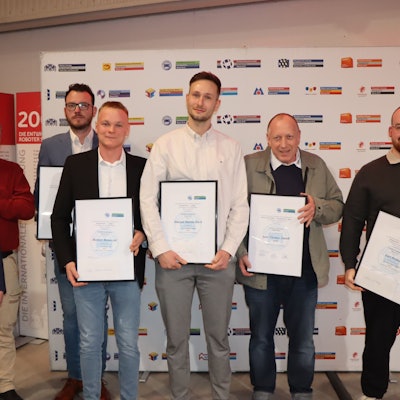 Männer mit Urkunden stehen nebeneinander.