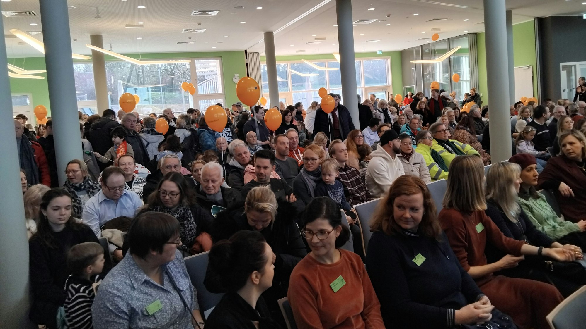 Orangefarbene Luftballons in einer voll besetzten Schulaula