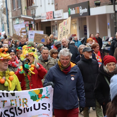 Auf dem Foto sind Demonstranten mit bunter Kleidung und Plakaten zu sehen.