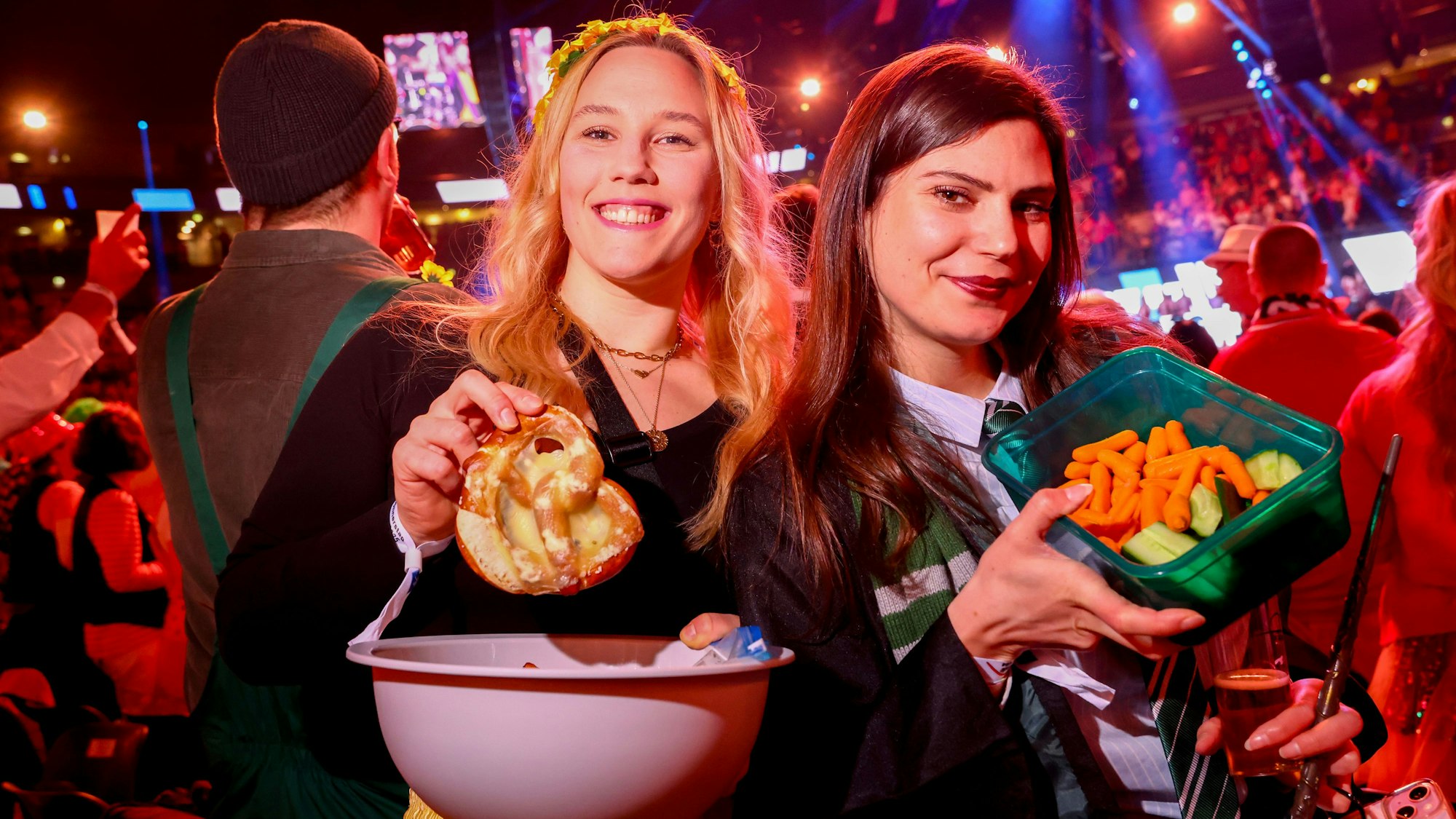Zwei Frauen mit Brezeln, Karotten und Gurke in Tupperdosen.
