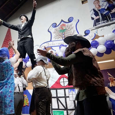 Verkleidete Männer tanzen auf der Bühne. Zwei von ihnen ermuntern das Publikum zum Mitklatschen.