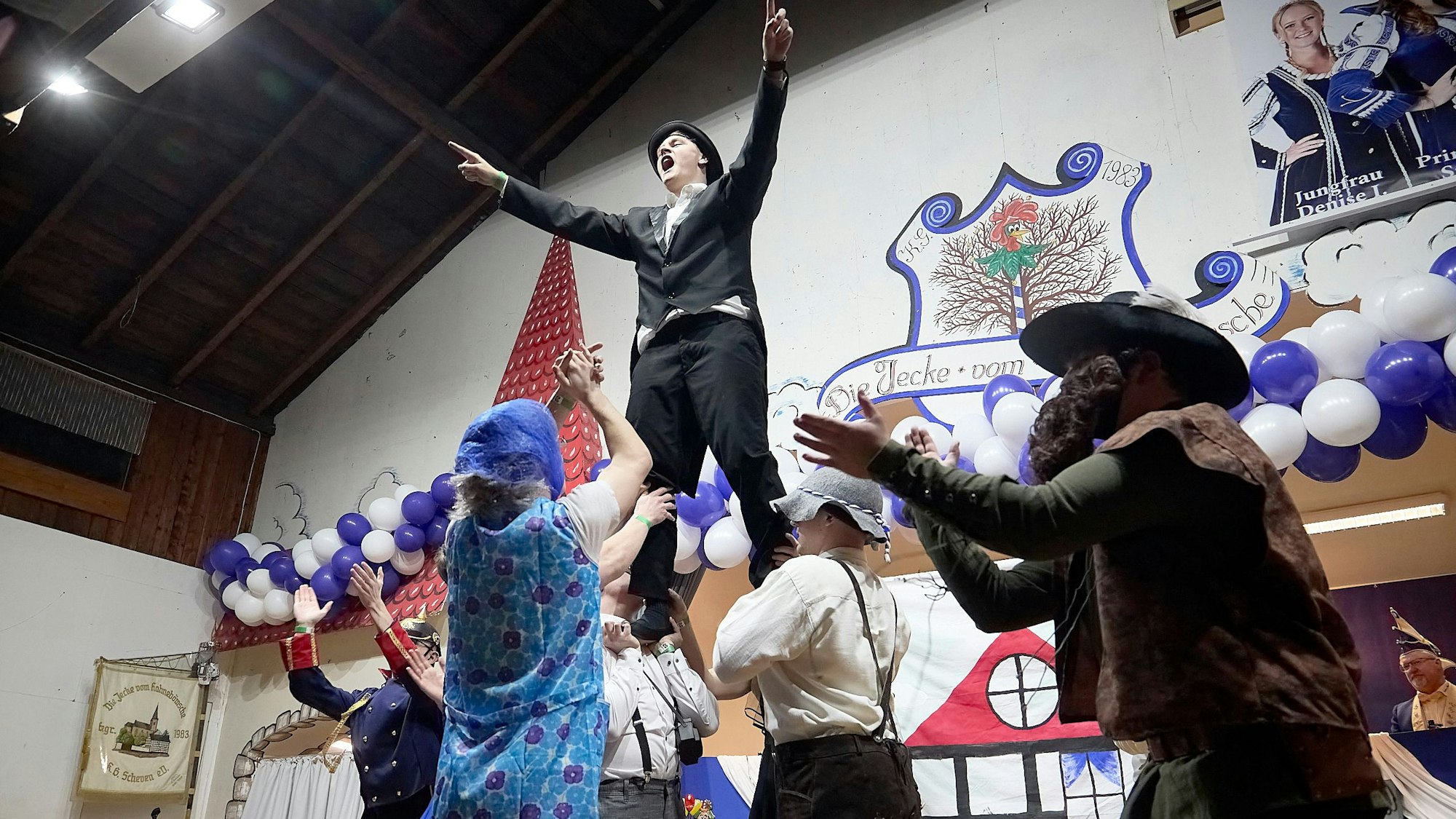 Verkleidete Männer tanzen auf der Bühne. Zwei von ihnen ermuntern das Publikum zum Mitklatschen.