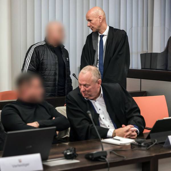Der Hauptangeklagte (hinten, links) spricht im Gerichtssaal mit seinem Verteidiger Oliver Doelfs (hinten, rechts), während vorne ein Angeklagter (M) mit seinem Verteidiger Hartmut Moyzio (vorne, rechts) spricht.