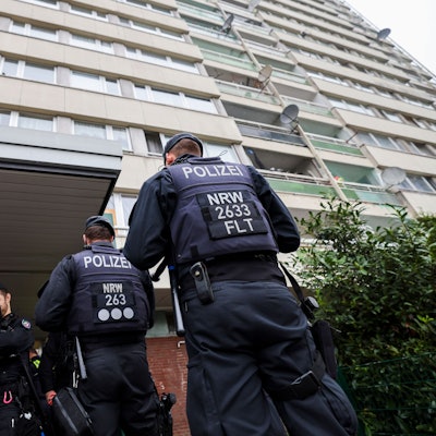 Bei einer Meldekontrolle durch verschiedene Behörden am Problem-Hochhaus „Weißer Riese“ in Duisburg stehen Polizisten vor dem Hochhauskomplex.