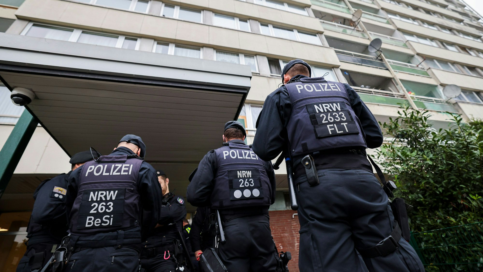 Bei einer Meldekontrolle durch verschiedene Behörden am Problem-Hochhaus „Weißer Riese“ in Duisburg stehen Polizisten vor dem Hochhauskomplex.