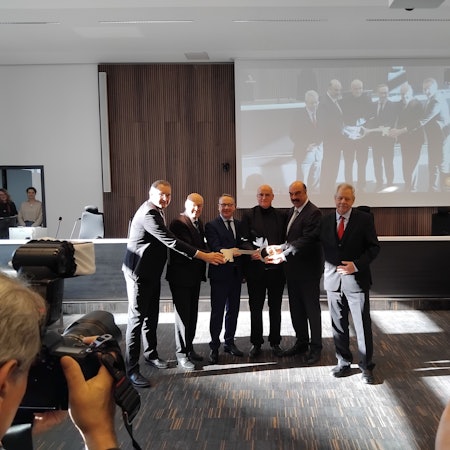 Sechs Männer halten einen symbolischen Schlüssel