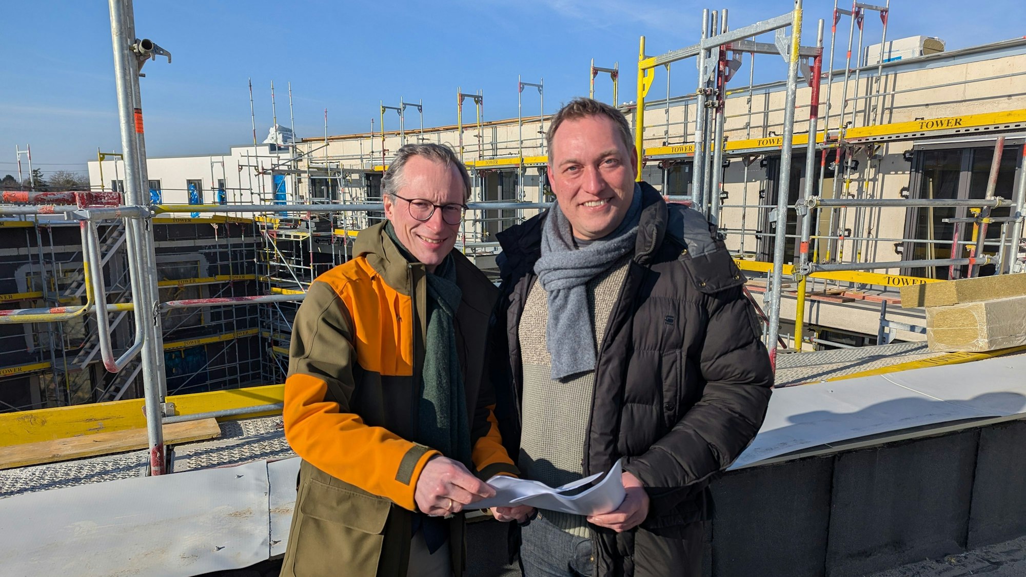 Das Foto zeigt zwei Männer auf einer Dachterrasse des Rohbaus.