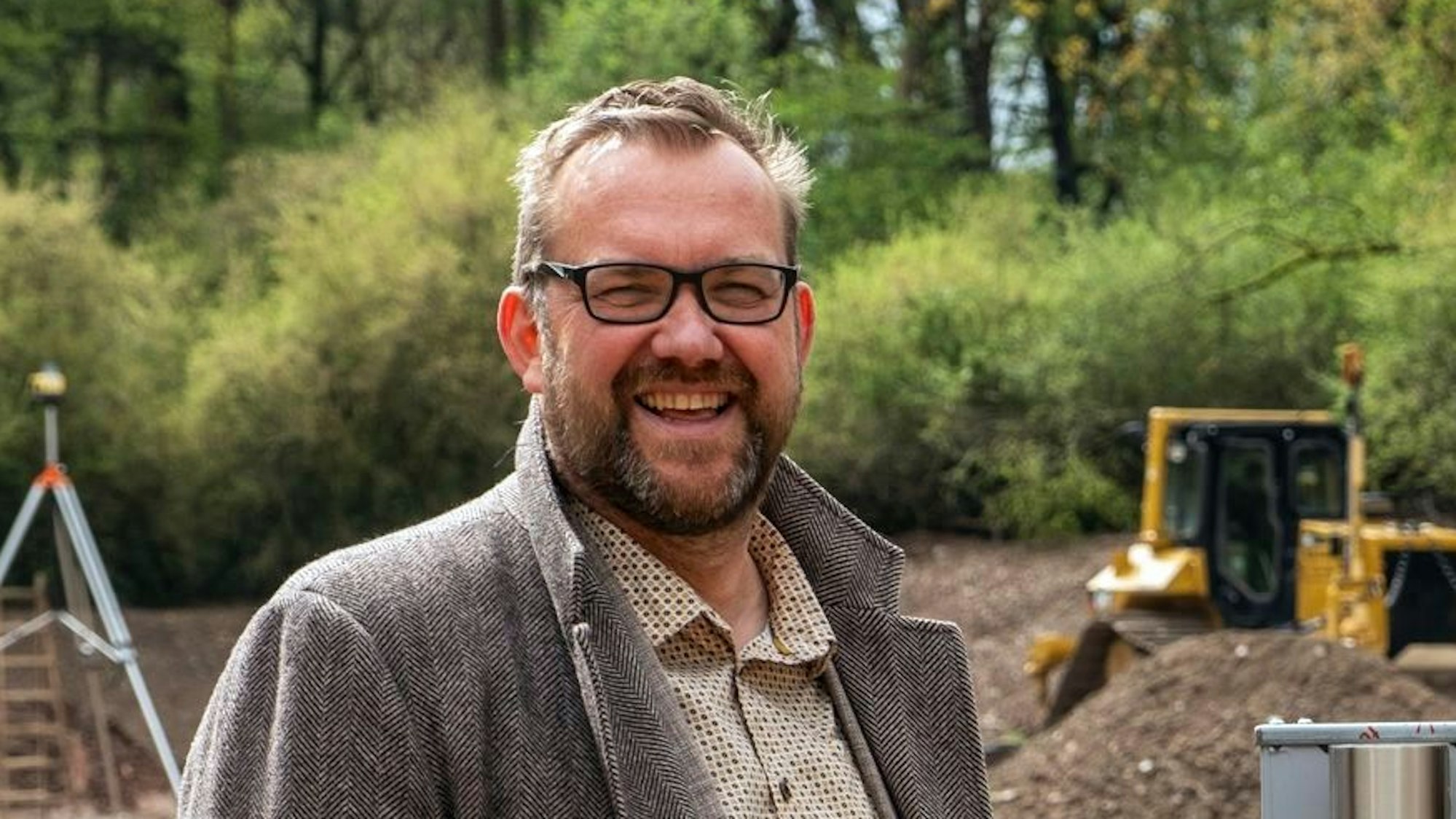 Das Archivbild zeigt Thomas Hambach, der einen Fischgratmantel trägt und auf einer Baustelle steht.