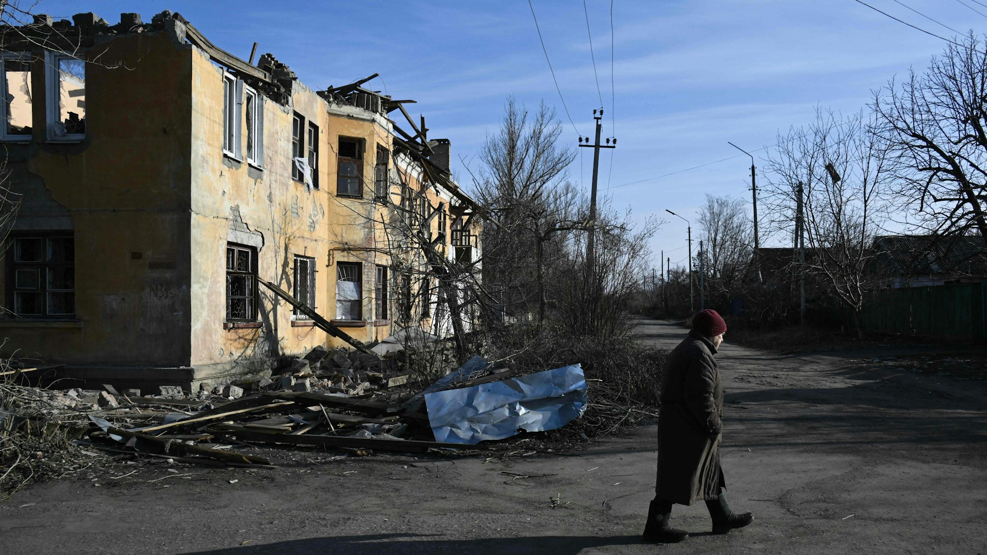 Ein Anwohner geht an einem schwer beschädigten Haus entlang.