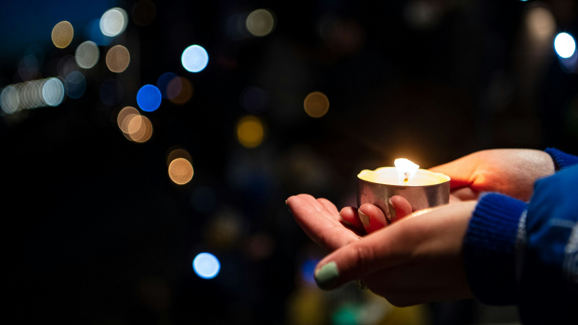Eine Teilnehmerin einer Lichterketten-Aktion am Weserufer hält eine Kerze in der Hand.