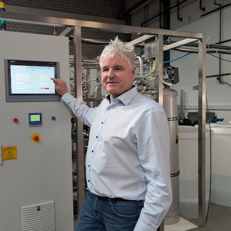 Ein Mann zeigt auf einen Bildschirm an einer technischen Anlage.