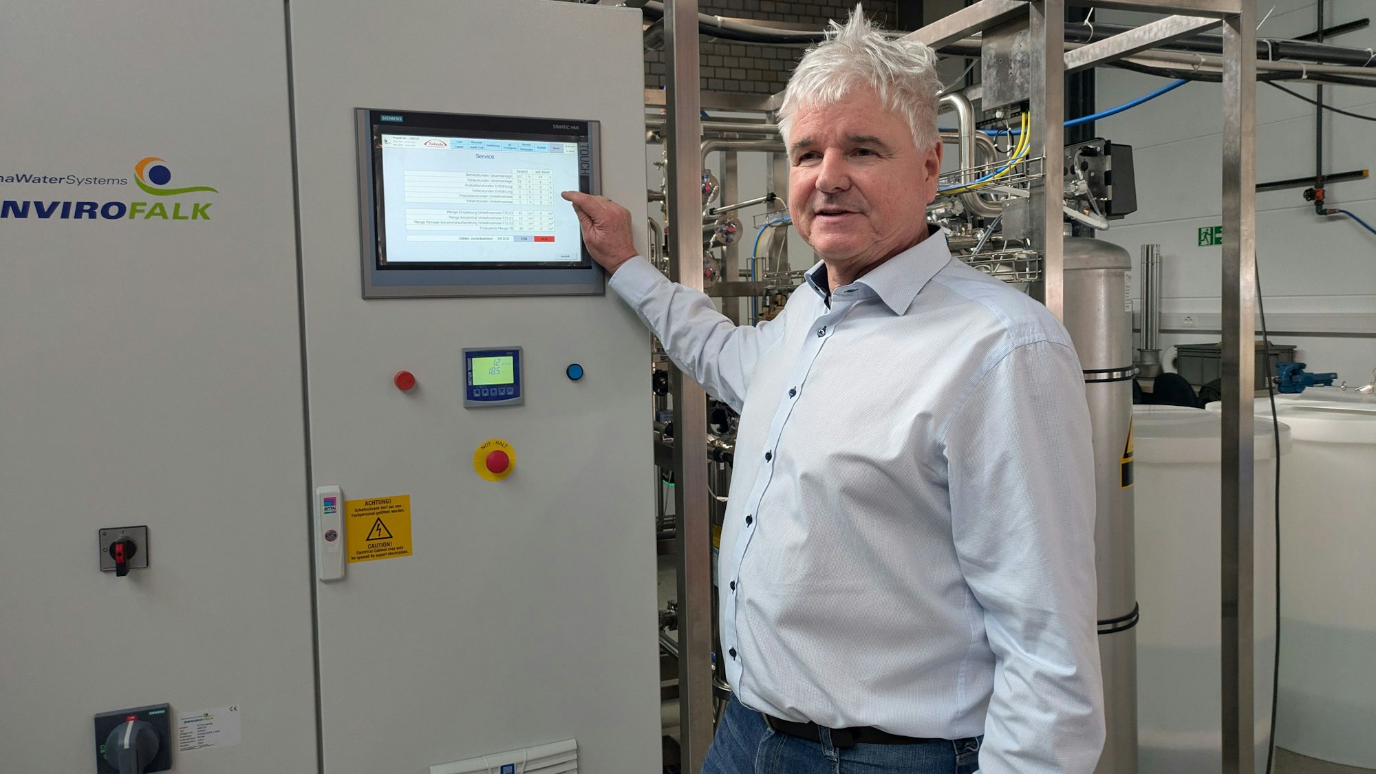 Ein Mann zeigt auf einen Bildschirm an einer technischen Anlage.