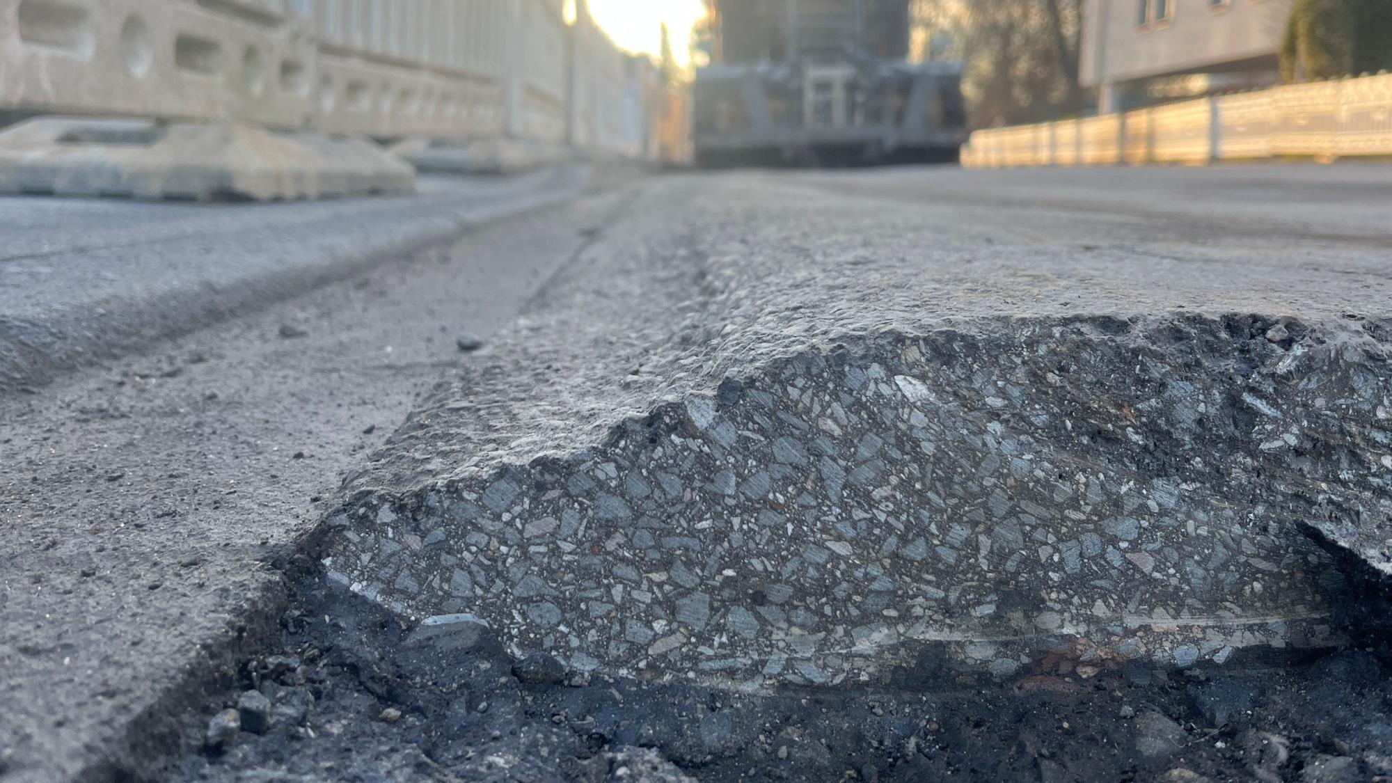Vor einer Grundstückseinfahrt wölbt sich der Asphalt hoch.
