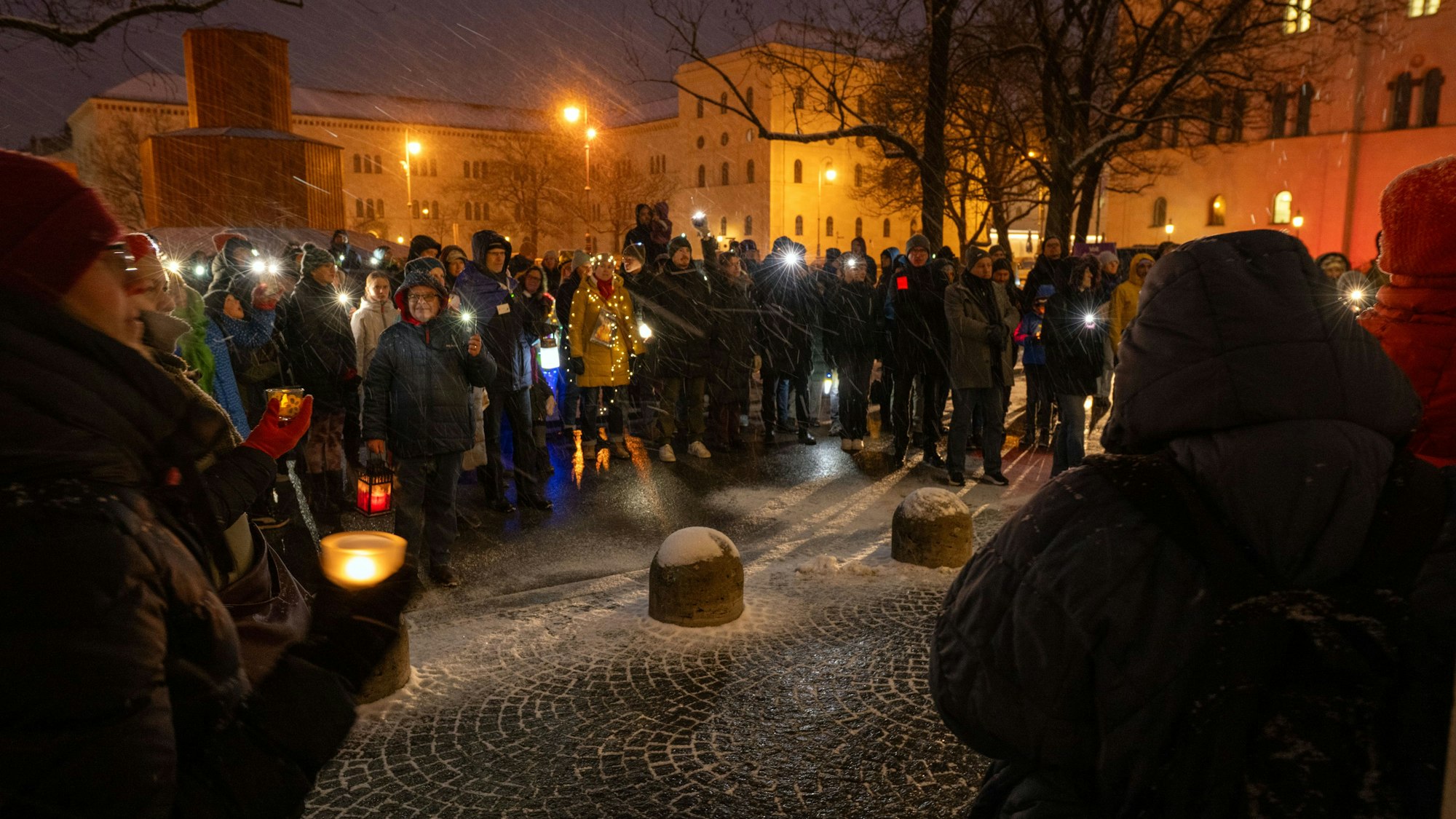 16.02.2025, Bayern, München: Männer und Frauen leuchten mit Taschenlampen, Smartphones, Lichterketten und anderen Leuchtmitteln am Geschwister-Scholl-Platz in München. Unter dem Motto "Nie wieder ist jetzt" haben sich zahlreiche Menschen versammelt, um ein Zeichen zu setzen gegen Hass und Hetze sowie für Demokratie und Menschenrechte. Dabei gedenken sie auch der Opfer des Anschlags vom 13. Februar 2025, als ein Auto in eine ver.di-Demonstration gerast ist. Foto: Pia Bayer/dpa +++ dpa-Bildfunk +++