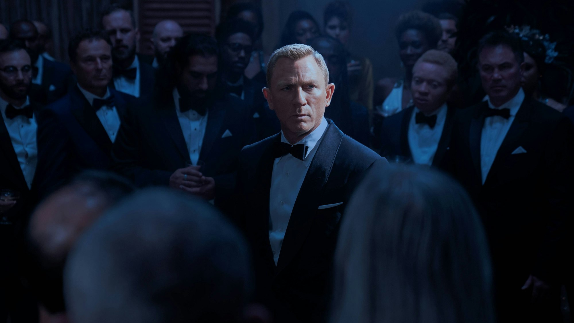 Daniel Craig als James Bond inmitten anderer Smoking-Träger.