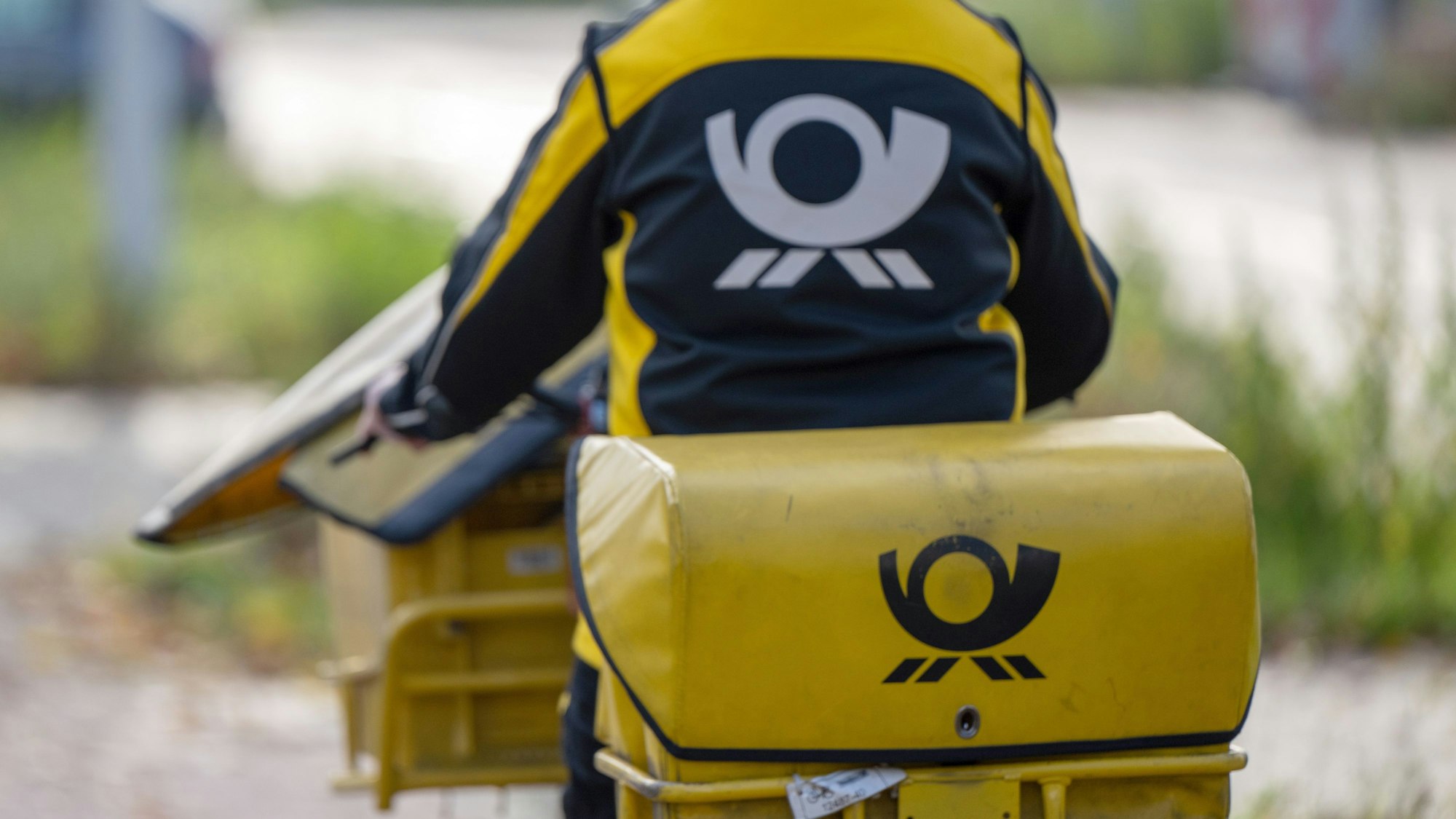 Eine Briefträgerin der Deutschen Post fährt auf ihrem Postfahrrad.