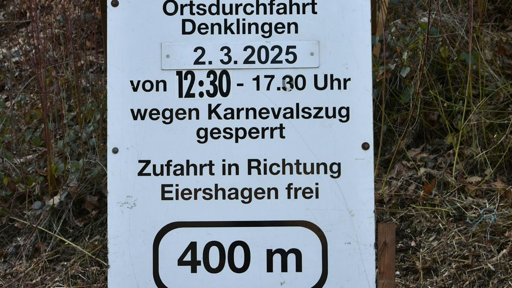 Ein Schild in Reichshof-Denklingen weist darauf hin, wann die Ortsmitte wegen des Karnevalszuges für den Autoverkehr gesperrt ist.