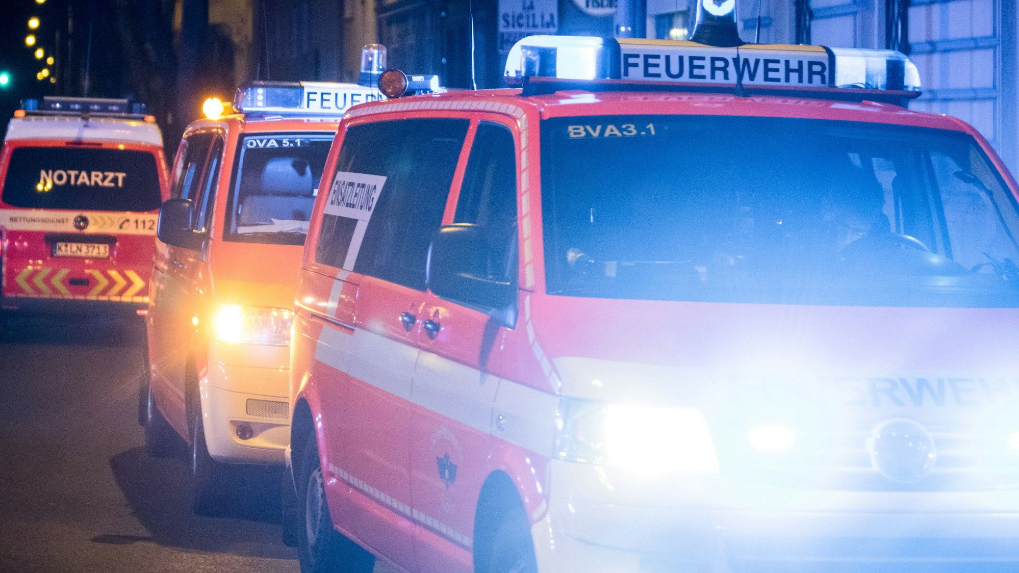 Feuerwehrwagen stehen mit leuchtenden Scheinwerfern am Straßenrand.